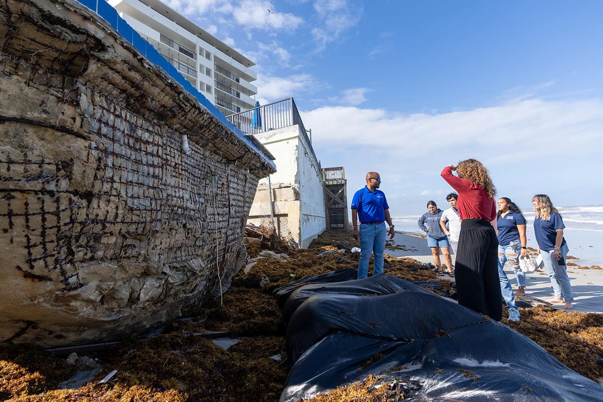 Embry-Riddle Professor Siddharth Parida and students involved in the Living Seawall project look at a site where storm surge has ripped away the beach-facing side of a swimming pool on Daytona Beach’s shoreline