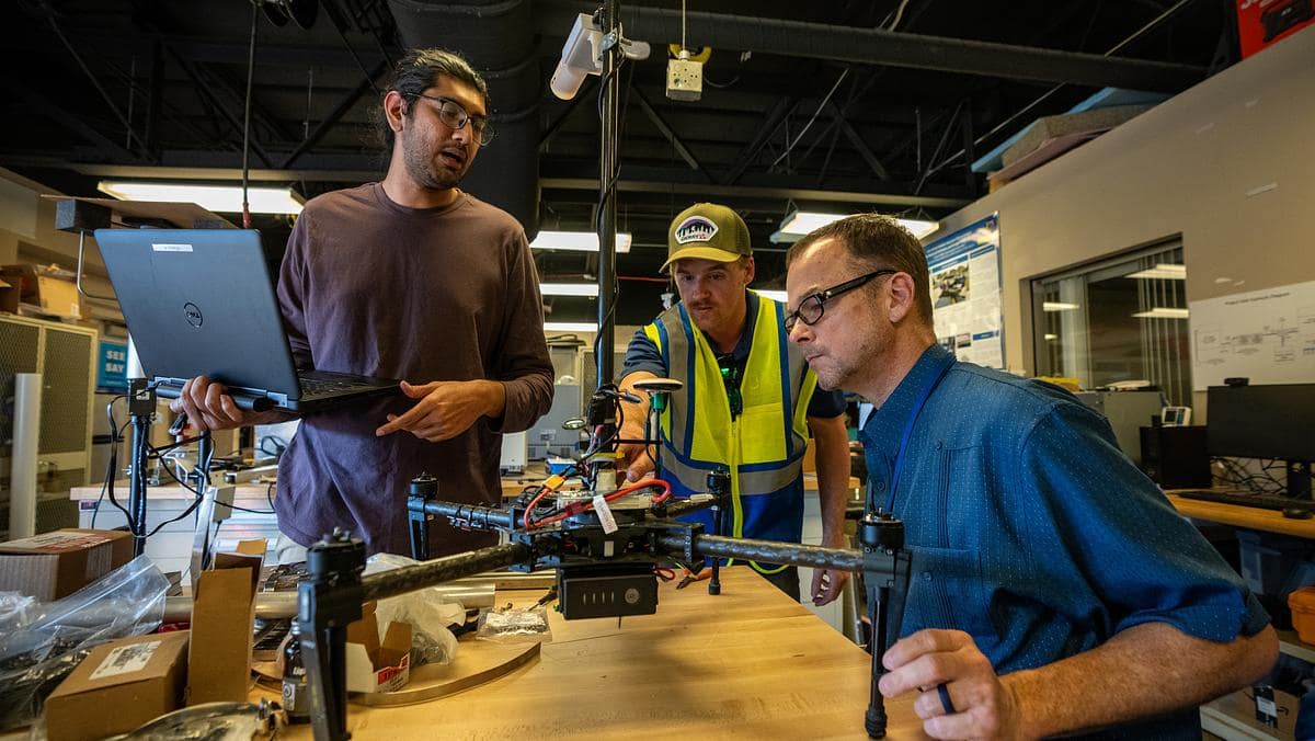 Dr. Avinash Muthu Krishnan, graduate researcher Jeremy Copenhaver and Dr. Marc Compere work on a weather-sensing drone that uses GPS to measure wind speed