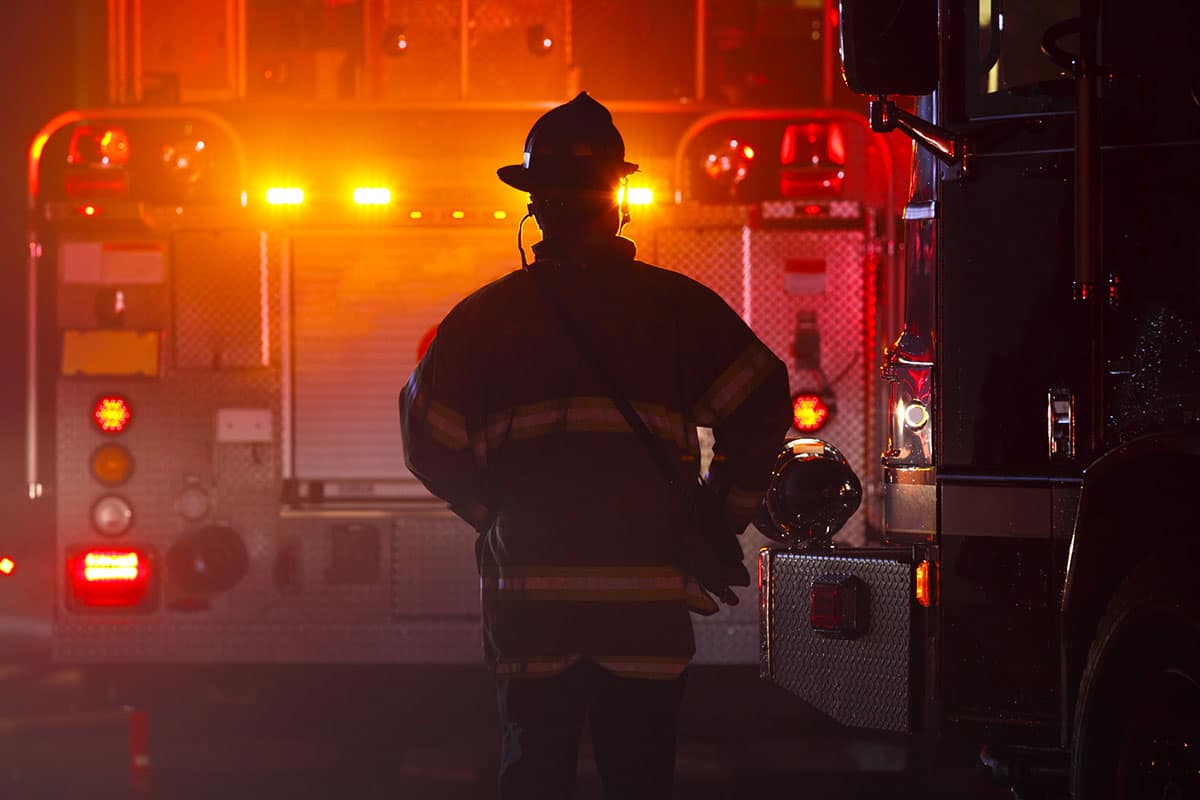 Firefighter silhouette with fire truck in the background