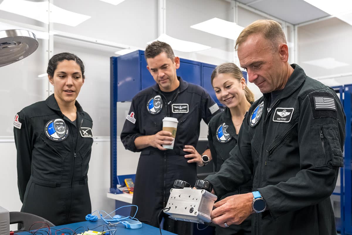 Polaris Dawn Mission Pilot Scott Poteet (right) inspects the LLAMAS camera unit