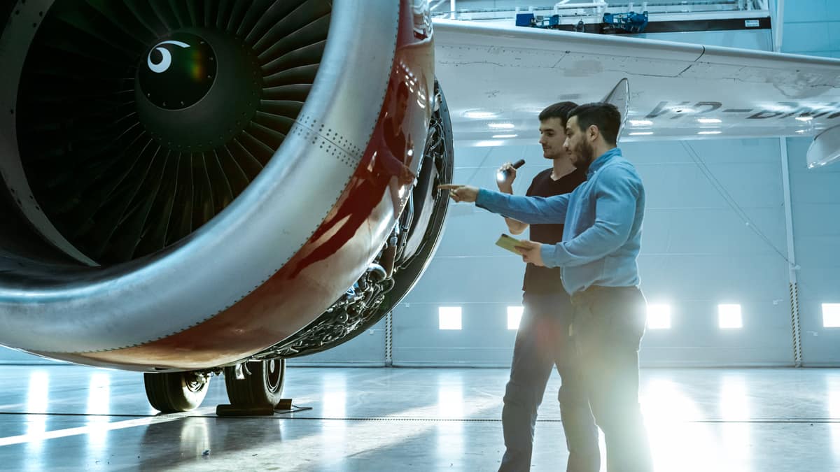 Two men look at a jet engine.
