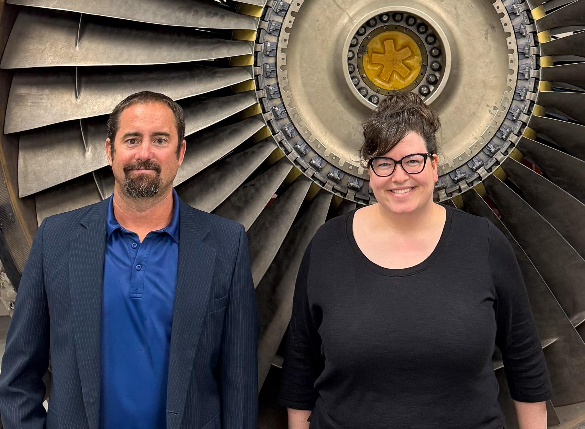 Drs. Sandra Boetcher and Mark Ricklick, standing in front of an aircraft turbine, received a $450,000 NSF grant to offer a student research collaboration with Brazilian colleagues on heat management of electric aircraft.