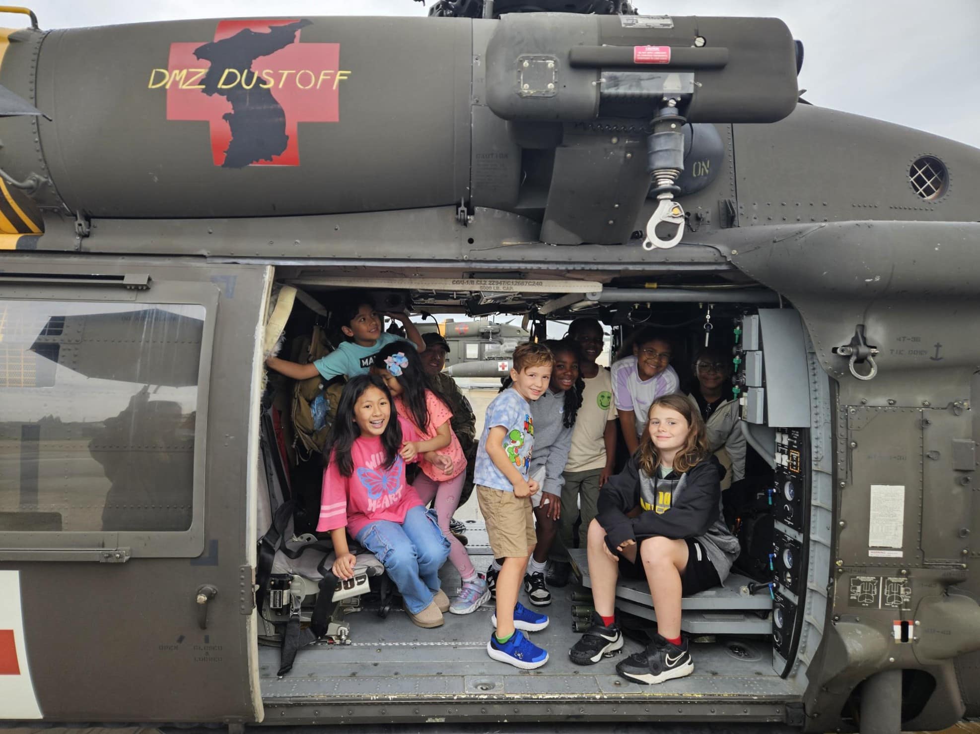 Military children hop aboard a UH-60 Blackhawk, which is ready for MEDEVAC takeoff within 15 minutes of a call, in honor of Girls in Aviation Day.