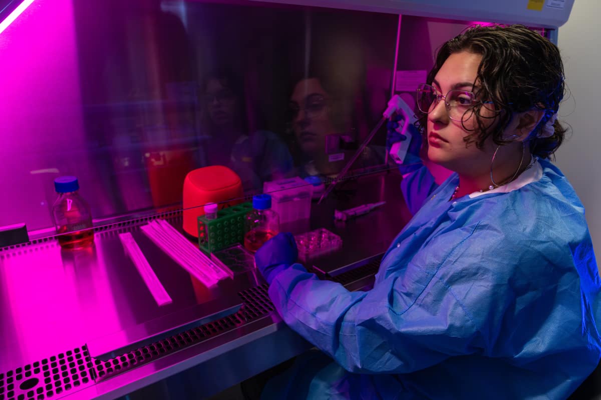 Aerospace Physiology student Mariposa Magee changes the cell culture media of lung epithelial cells in the sterile biosafety cabinet.