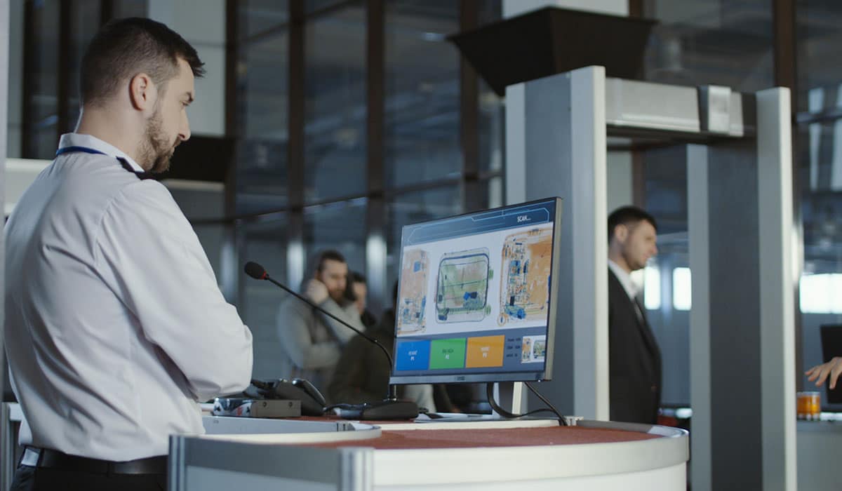 Airport security worker viewing luggage scan on monitor