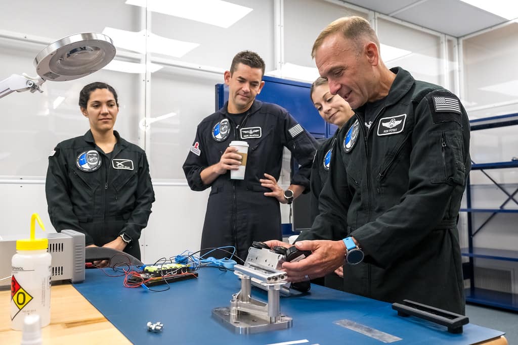 Polaris Dawn Mission Pilot Scott Poteet (right) inspects the LLAMAS camera unit, engineered by Embry-Riddle students under the direction of Dr. Troy Henderson, associate professor of Aerospace Engineering and director of the Space Technologies Lab. Alongside Poteet are fellow crewmembers Anna Menon, Jared Isaacman and Sarah Gillis.