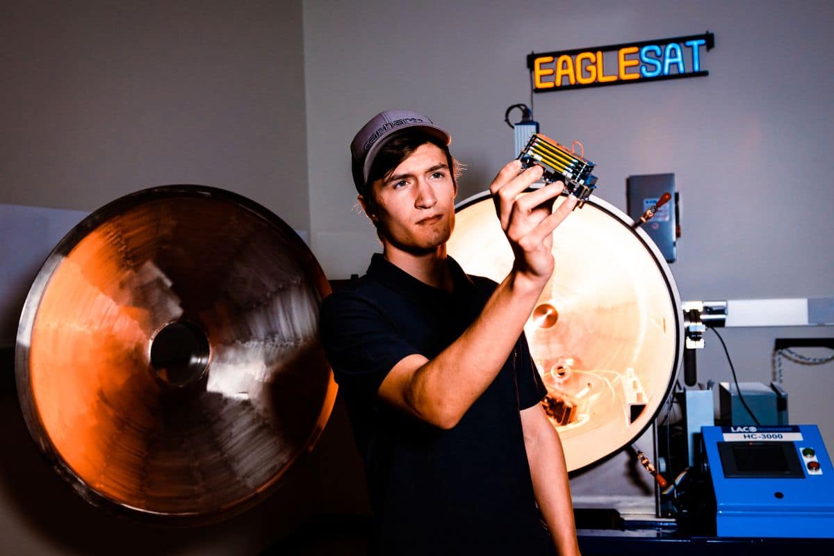 A student holds a cube satellite (CubeSat) designed, developed and tested by students at Embry-Riddle’s College of Engineering