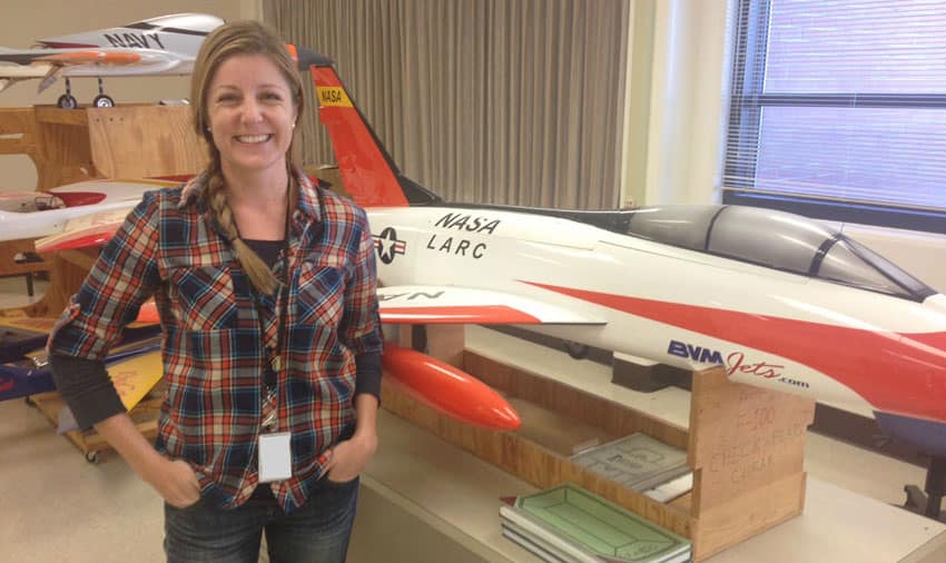Jill Brown, NASA engineer and Worldwide student, stands in front of a model jet