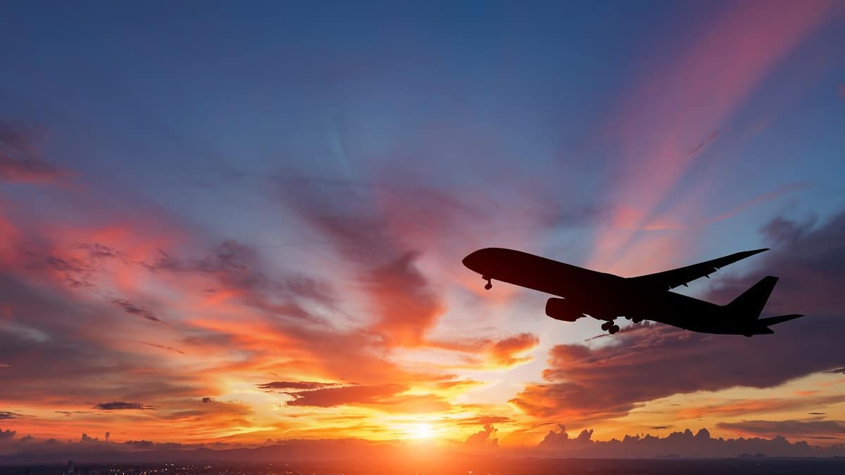 Plane flies past the setting sun