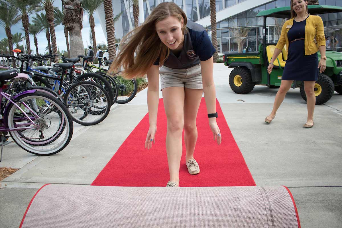 A student rolls out the red carpet for the David B. Omaley College of Business dedication.