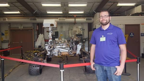 Embry-Riddle Eagle Matthew Demi Vis, now an avionics engineer at the Jet Propulsion Laboratory, at work with a copy of the Mars Curiosity Rover.