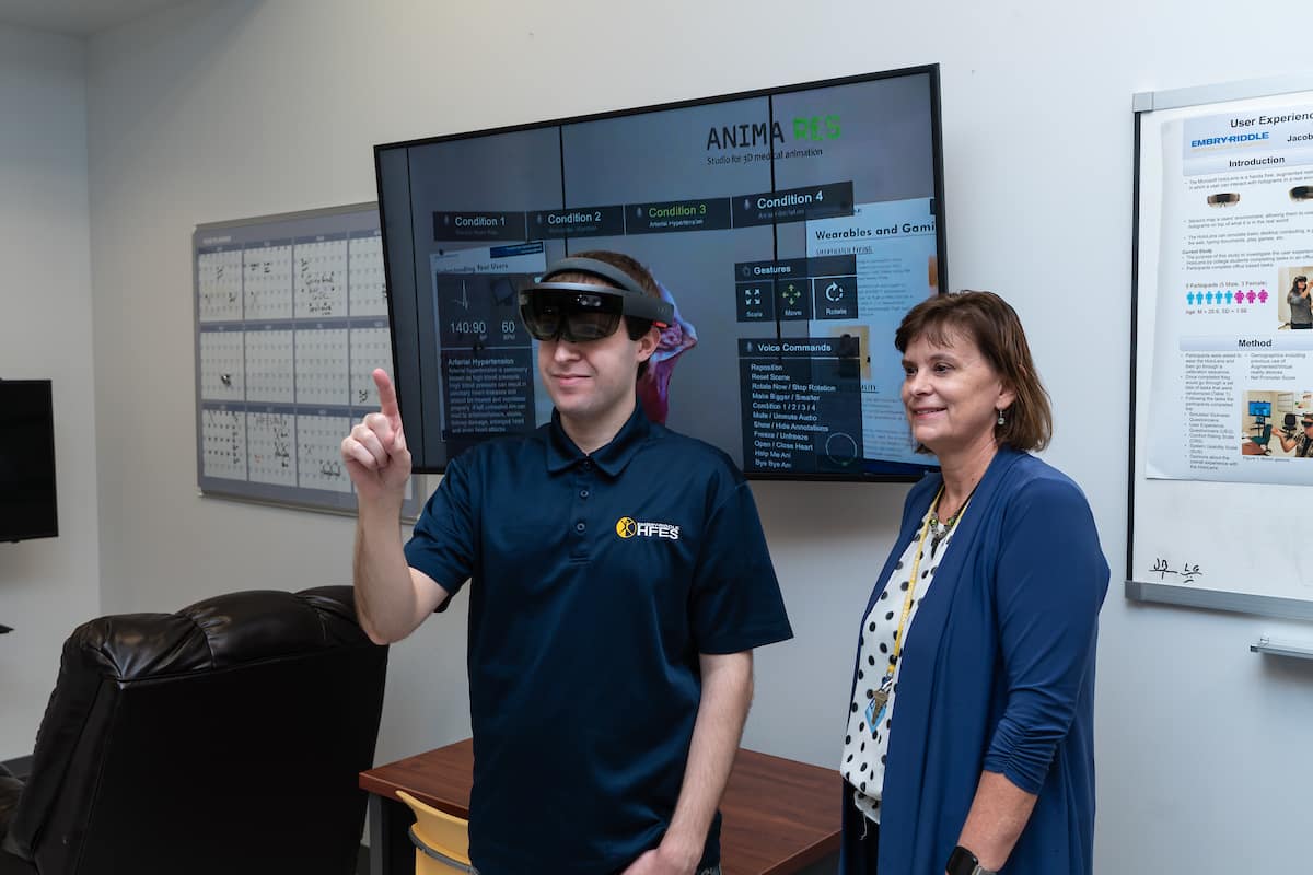 Dr. Barbara Chaparro, professor of Human Factors and Behavioral Neurobiology, coaches Ph.D. student William Shelstadt as he demonstrates a Microsoft HoloLens augmented reality headset connected to a medical training application in the RUX (Research in User eXperience) Lab.