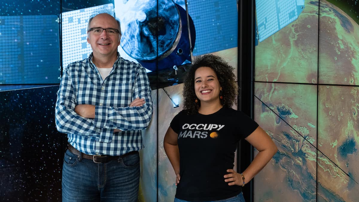 Dr. Edwin Mierkiewicz, associate professor of Physics, and Andréa Hughes, a Ph.D. candidate, pose with an image of NASA’s MAVEN spacecraft. (Photo: Embry-Riddle/Daryl LaBello)