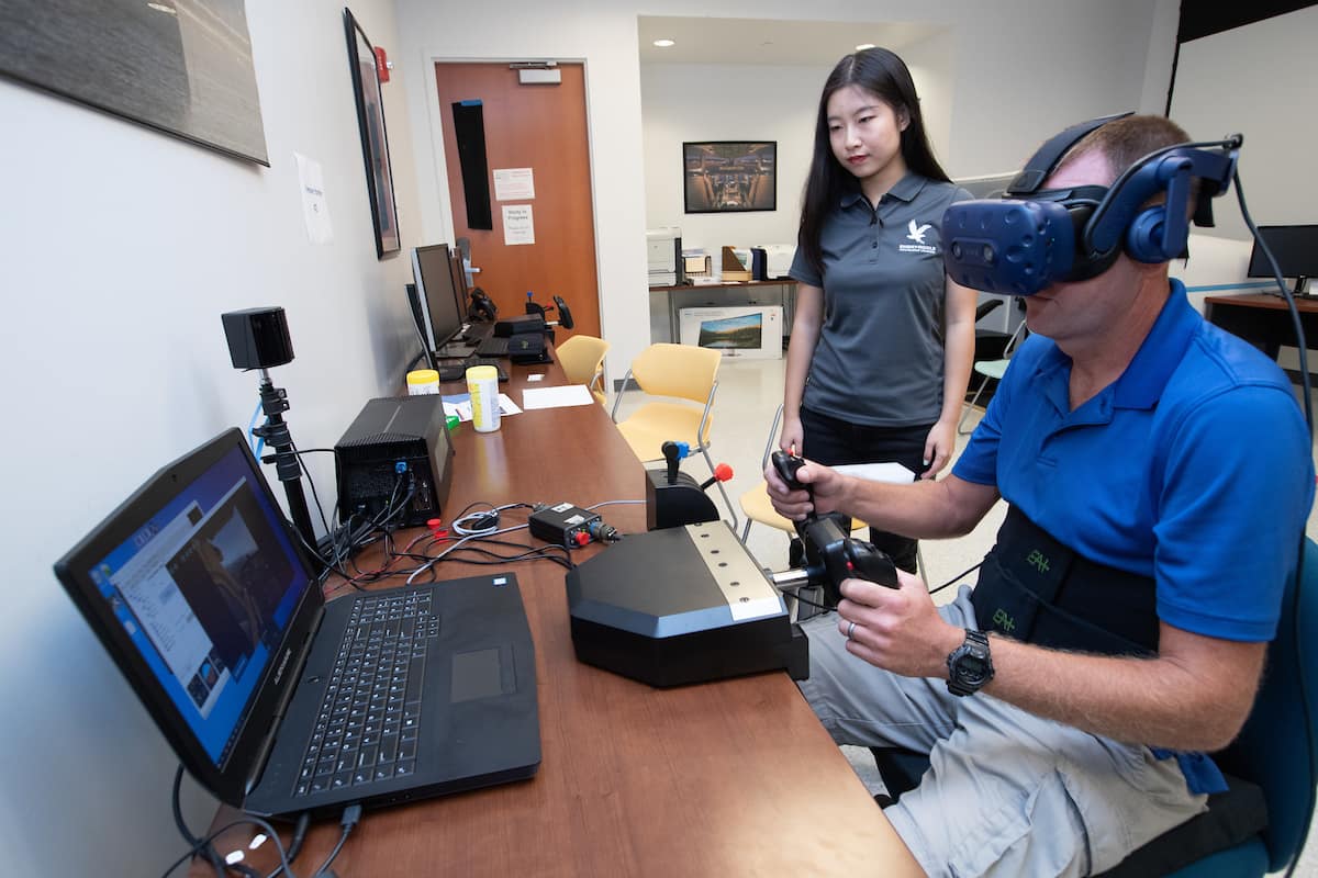 Graduate students Qianhong “Echo” Liu and Tyson Richards work on a virtual reality Spatial Disorientation Simulator.