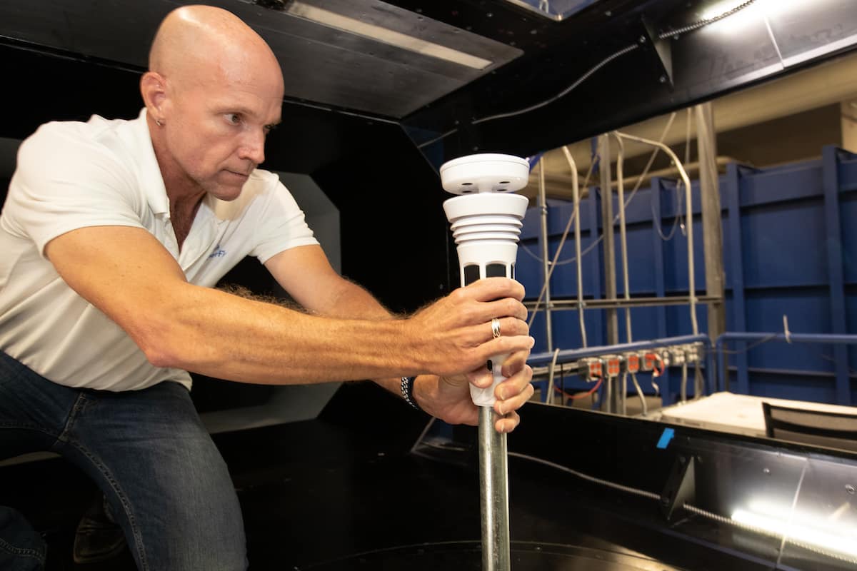 David St. John, technical product lead for WeatherFlow Inc., affixes the Tempest weather station inside the Subsonic Wind Tunnel Facility at the Micaplex, and then records his findings. (Photo: Embry-Riddle/David Massey)