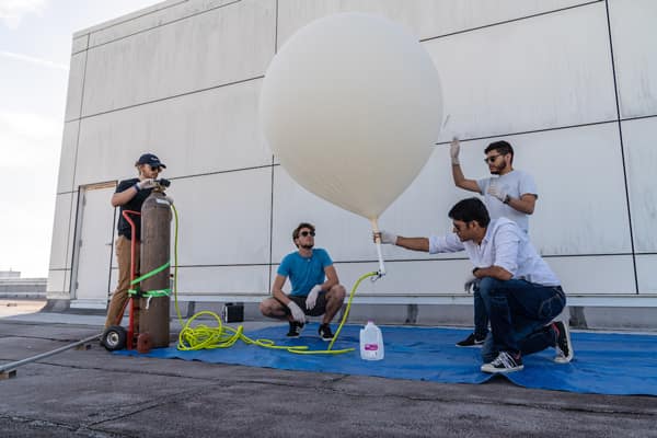 Dr. Aroh Barjatya (kneeling) and students (L-R): Christopher Swinford, Peter Douglass and Julio Guardado prepare a high-altitude balloon, which makes it possible to capture data on atmosphere turbulence.