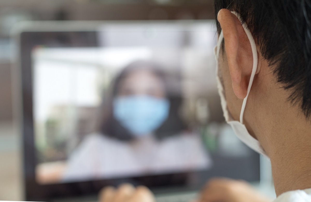 Asia man wear medical mask using notebook computer working for social distancing meeting online with social media application.