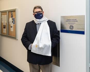 Bob Whetsell, director of Safety Programs at GE Aviation Digital Solutions, stands before the new GE Aviation Classroom at Embry-Riddle, donning an aviation scarf.