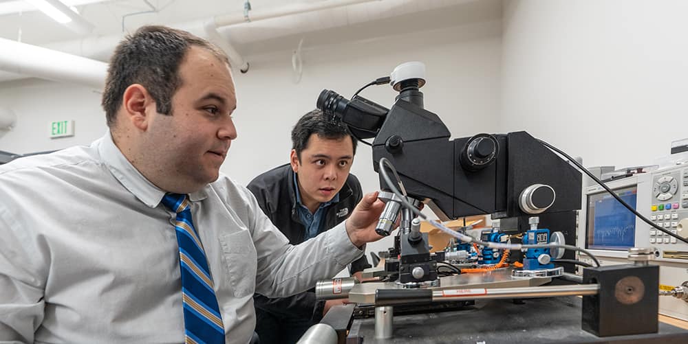 Dr. Eduardo Rojas works with PhD student Seng Loong (Hanson) on small antennas at the microscope station in the WIDE lab. January 8, 2020. (Embry-Riddle/Daryl LaBello)