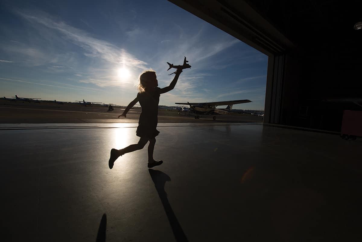 a child running with a toy airplane at a hangar