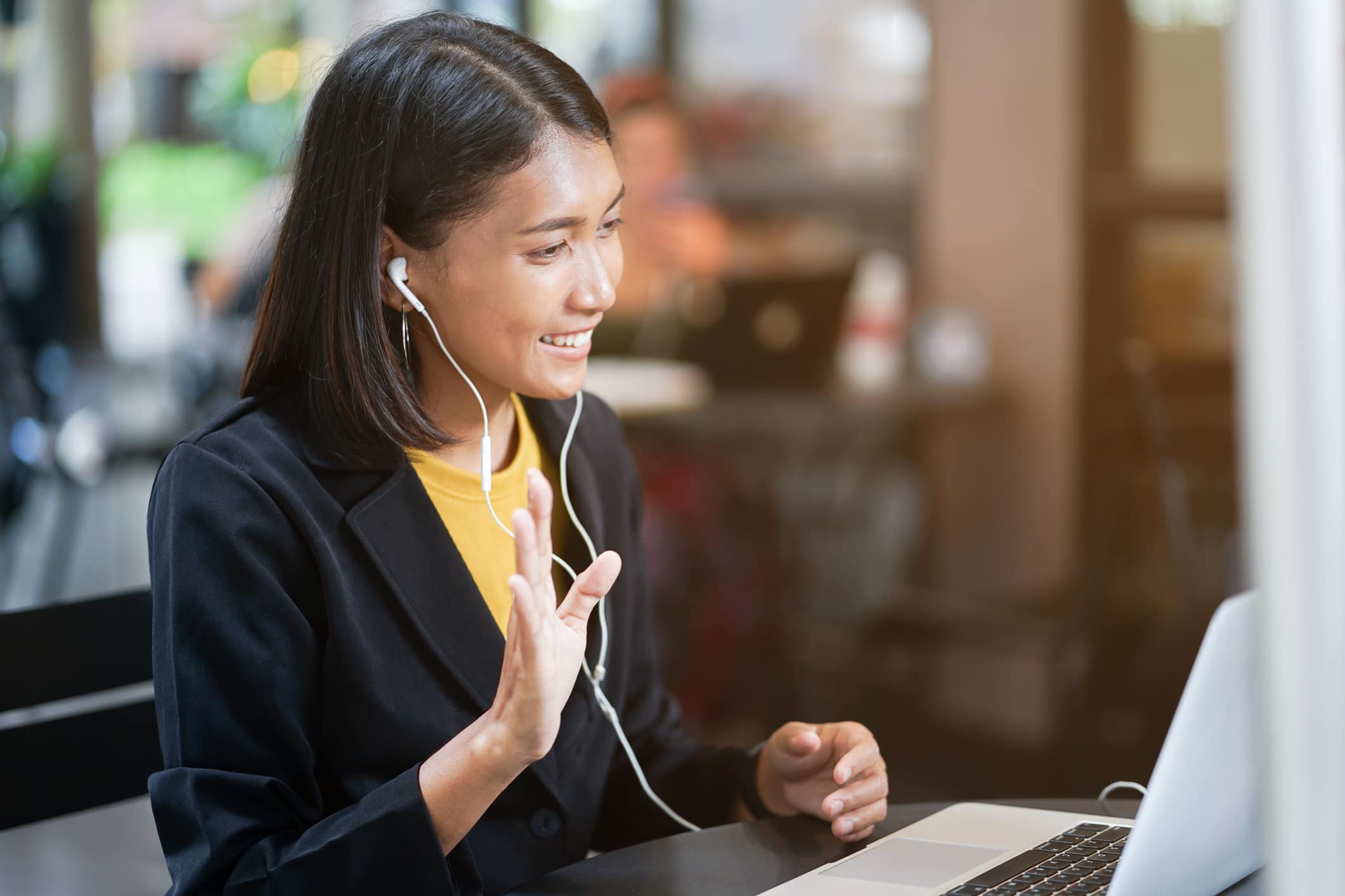 Woman wearing headphones gestures at a laptop