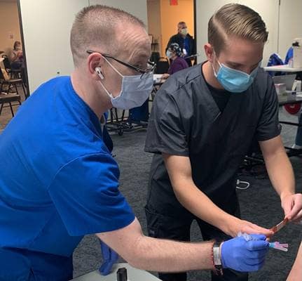 Embry-Riddle Aerospace Physiology student John Veracka (right) assists a healthcare professional at AdventHealth during a Covid-19 vaccine clinic. (Photo: Embry-Riddle)