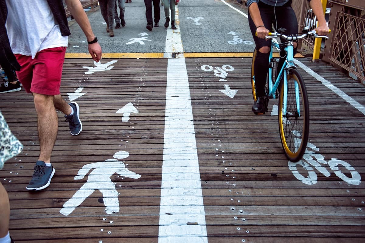 a close-up image of people's feet walking and bicycle wheels