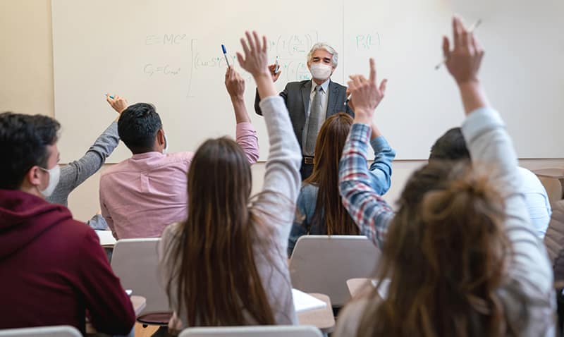 A masked instructor teaches class