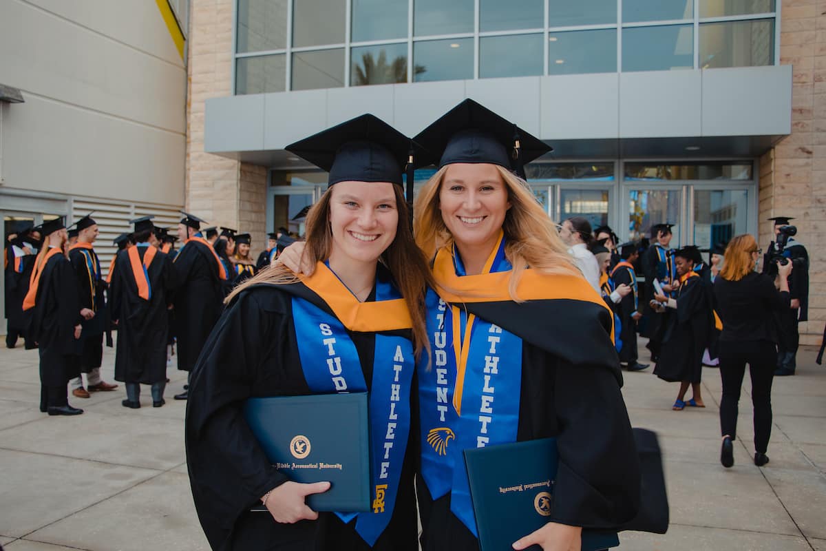 Two ERAU graduates hold their degrees