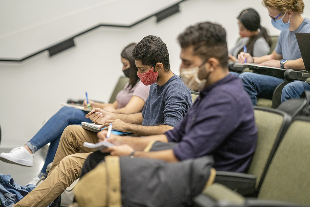 Masked students in auditorium classroom