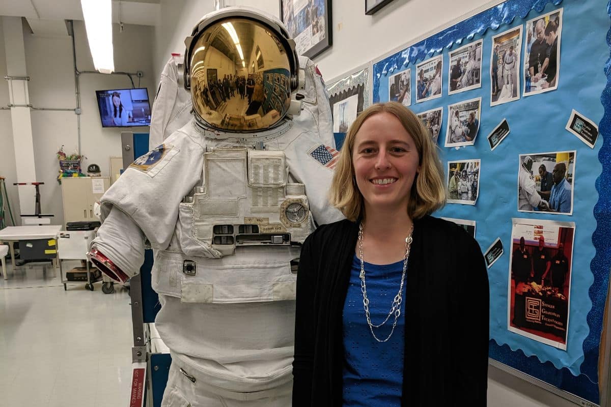 Dr. Kaela Martin standing beside a NASA space suit
